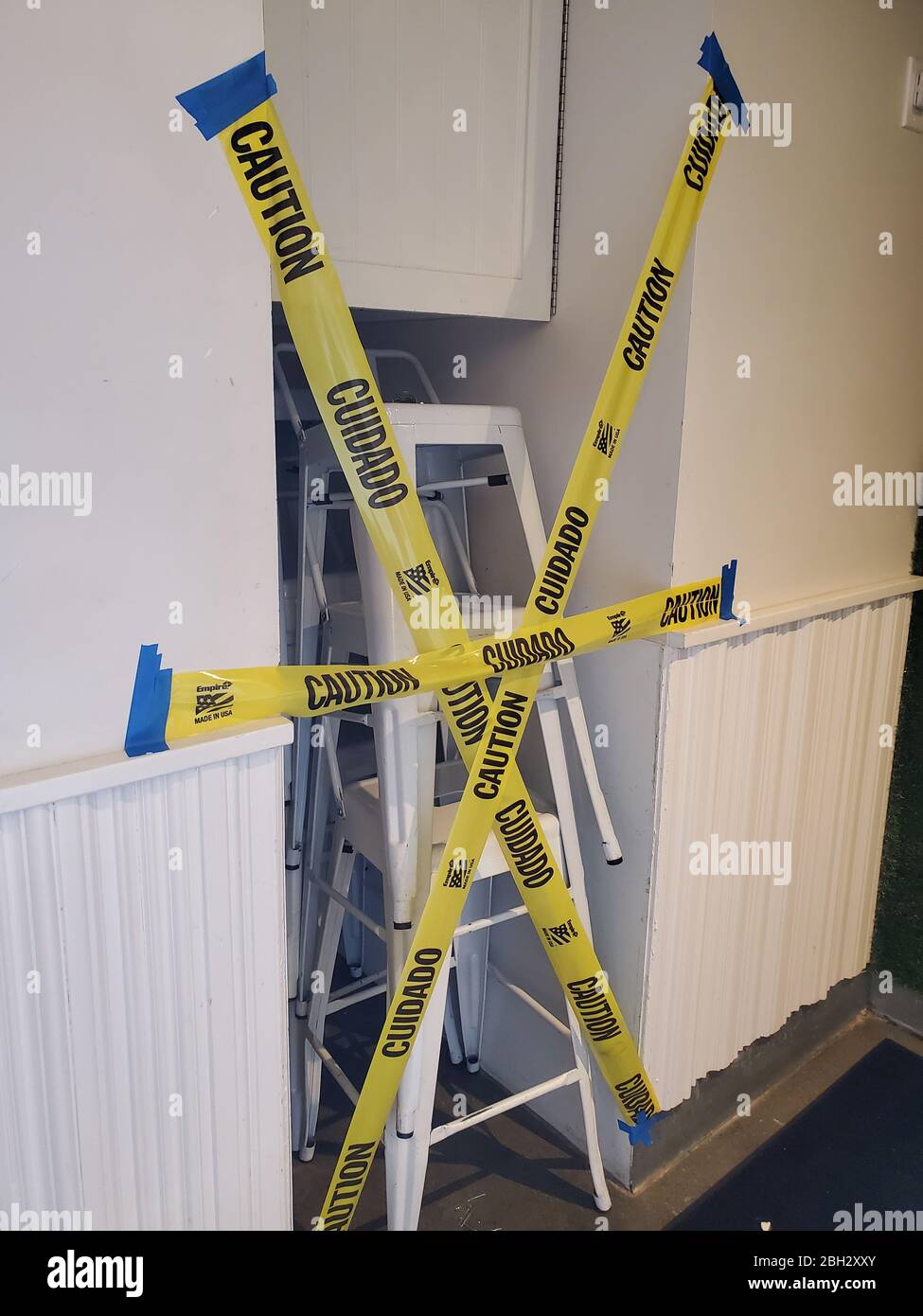 Le sedie della sala da pranzo sono collocate in un'area di deposito e coperte con nastro di attenzione per impedire l'uso da parte degli ospiti in un ristorante la cui sala da pranzo è stata chiusa a seguito di un ordine di rifugio in luogo durante uno scoppio del coronavirus COVID-19 nella Silicon Valley, Santa Clara County, Campbell, California, 28 marzo 2020. () Foto Stock