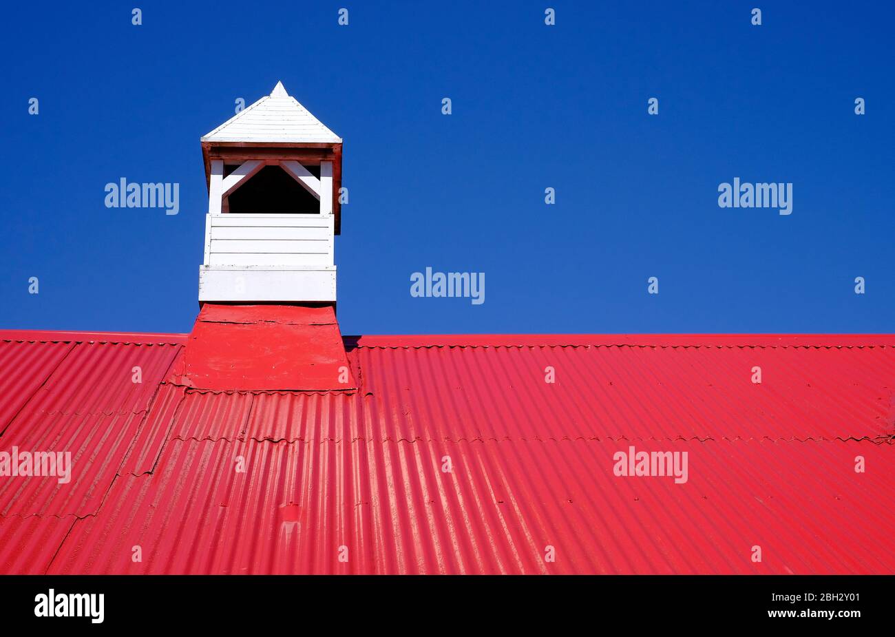 tetto in metallo ondulato dipinto di rosso e cielo blu sfondo Foto Stock