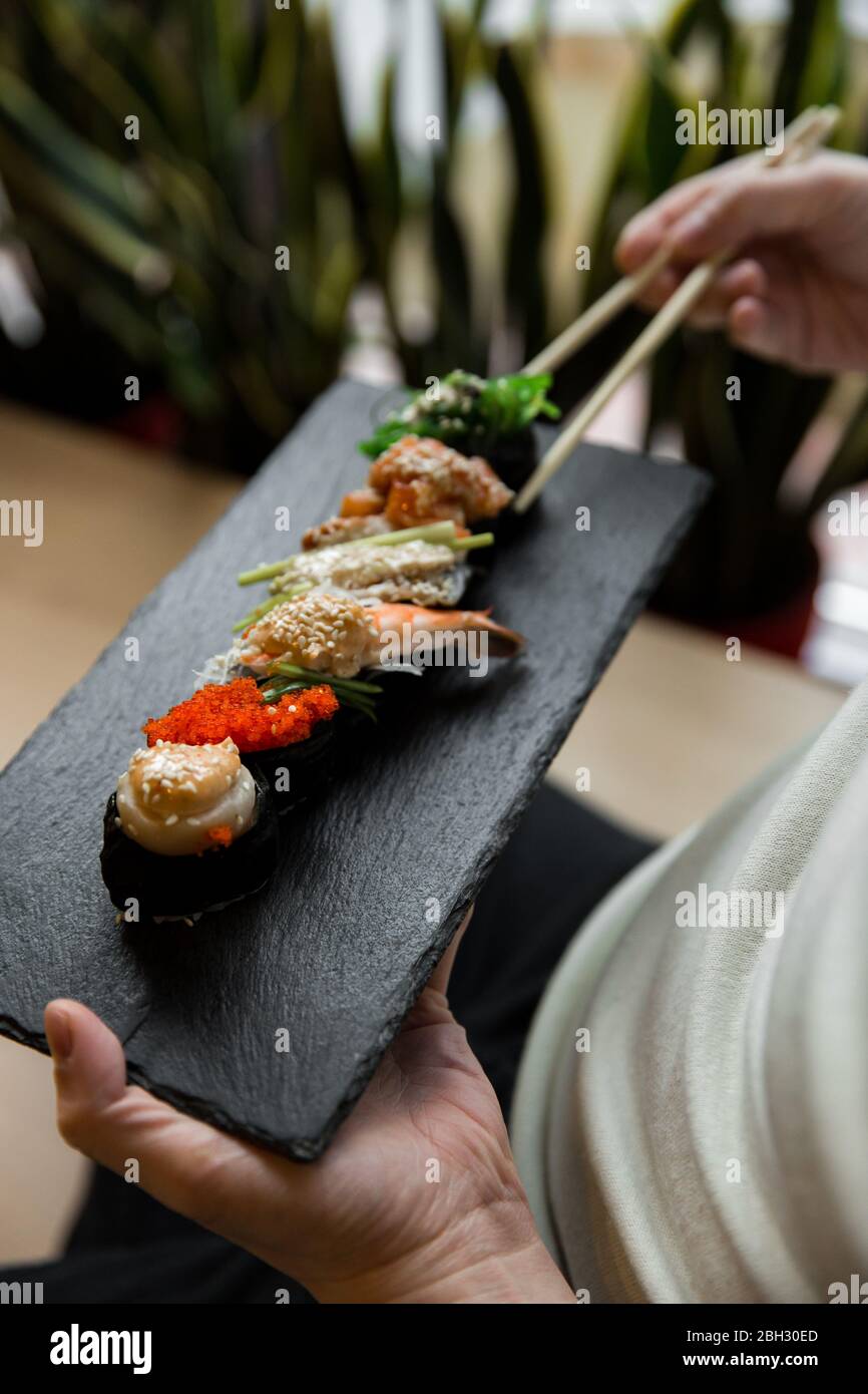 Assortimento di maki gunkan di sushi freschi con pesce. Set di gunkan in mano. Messa a fuoco selettiva. Foto Stock