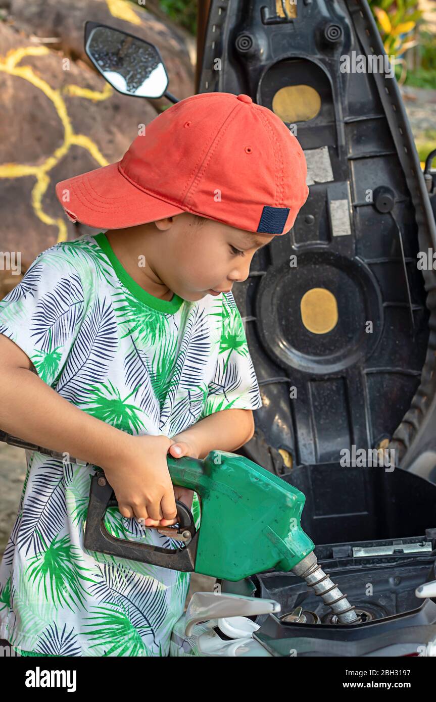 Ragazzo asiatico il rifornimento carburante in moto Foto Stock