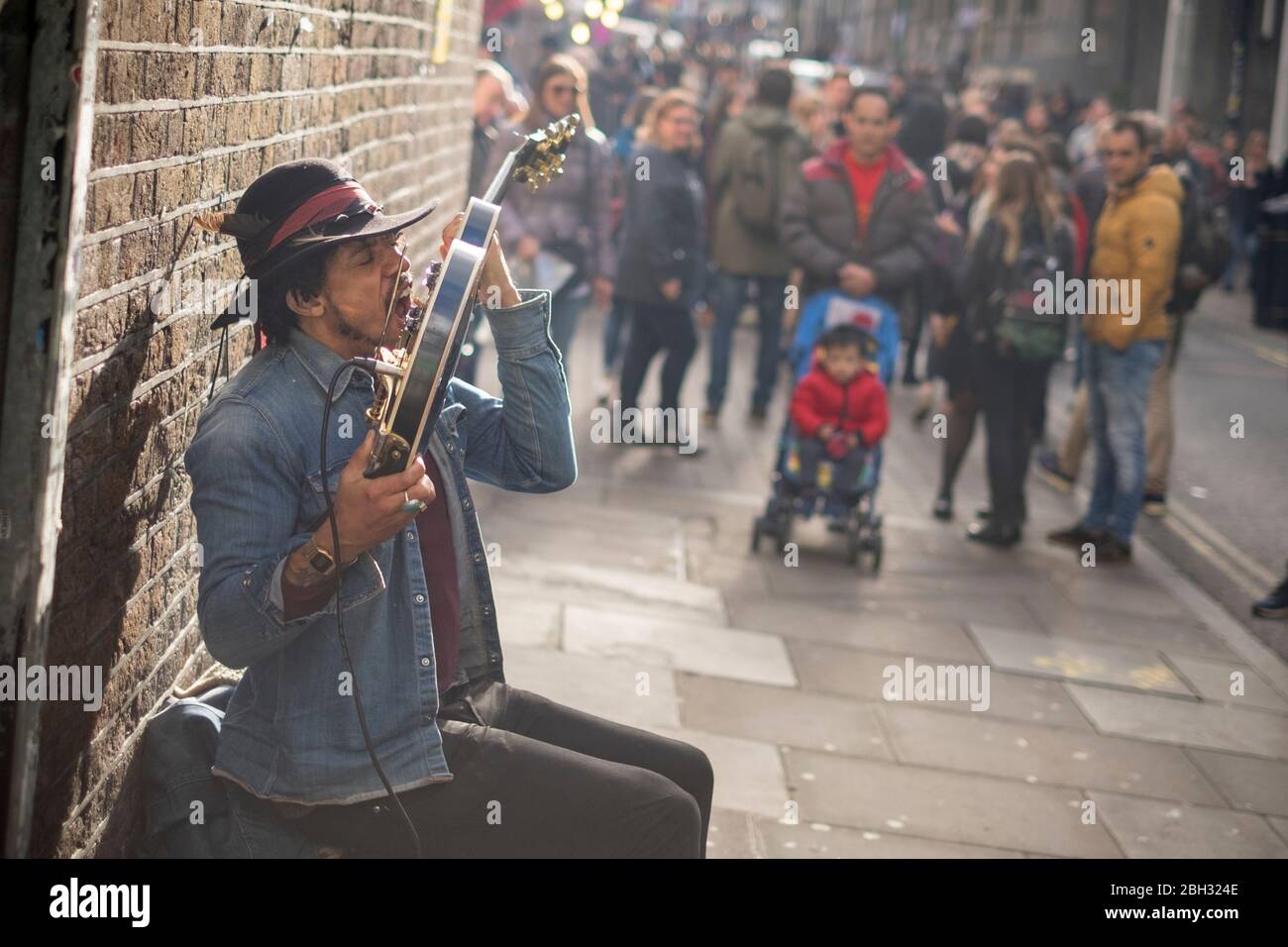 Un sosia di Jimi Hendrix che suona la chitarra con i denti e con una folla  che guarda, Brick Lane, Londra Foto stock - Alamy
