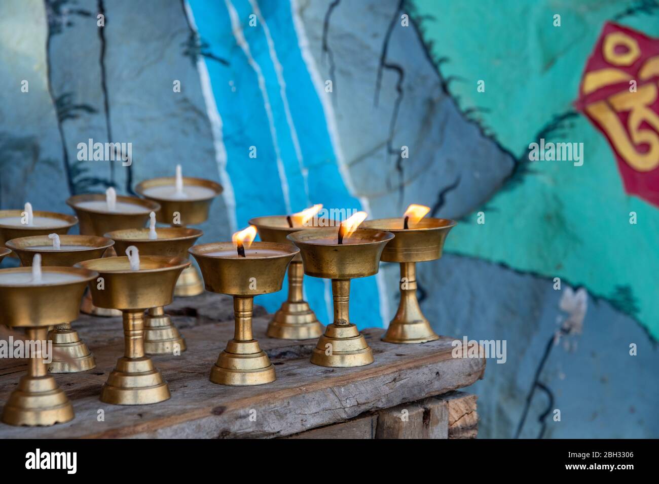 Candele votive bruciano su un altare di un tempio indù lungo la strada che sale a Namobuddha Foto Stock
