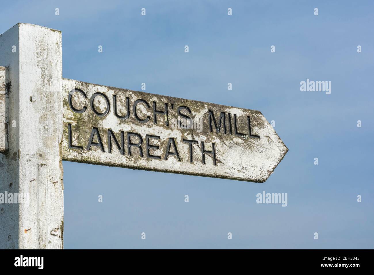 Locale rurale Cornish Road segno per Couch's Mill e Lanreath - ambientato contro il cielo blu soleggiato Springtime. Foto Stock