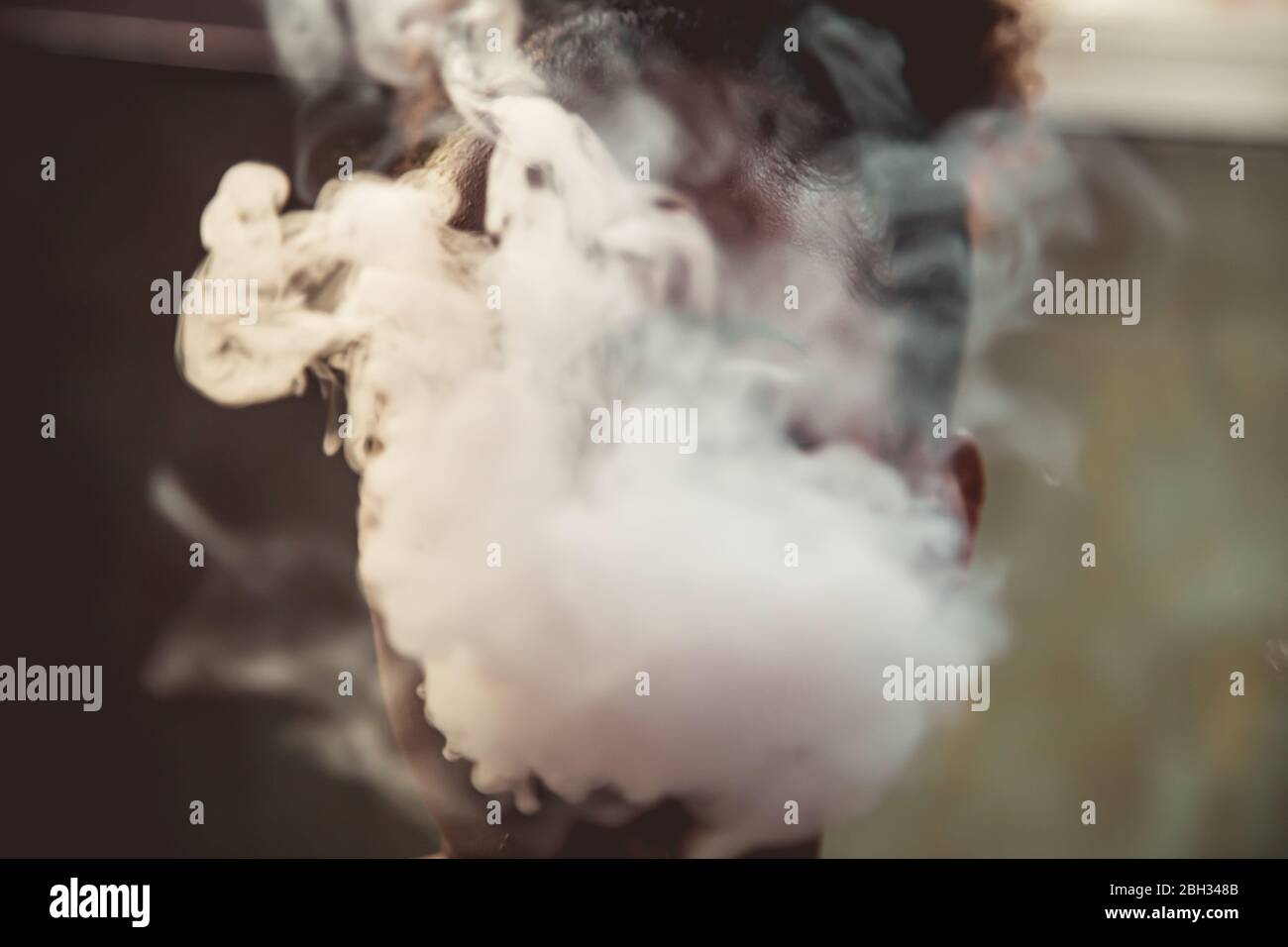 Ritratto di una ragazza nera che fuma dalla sua bocca che gli copre completamente il volto Foto Stock