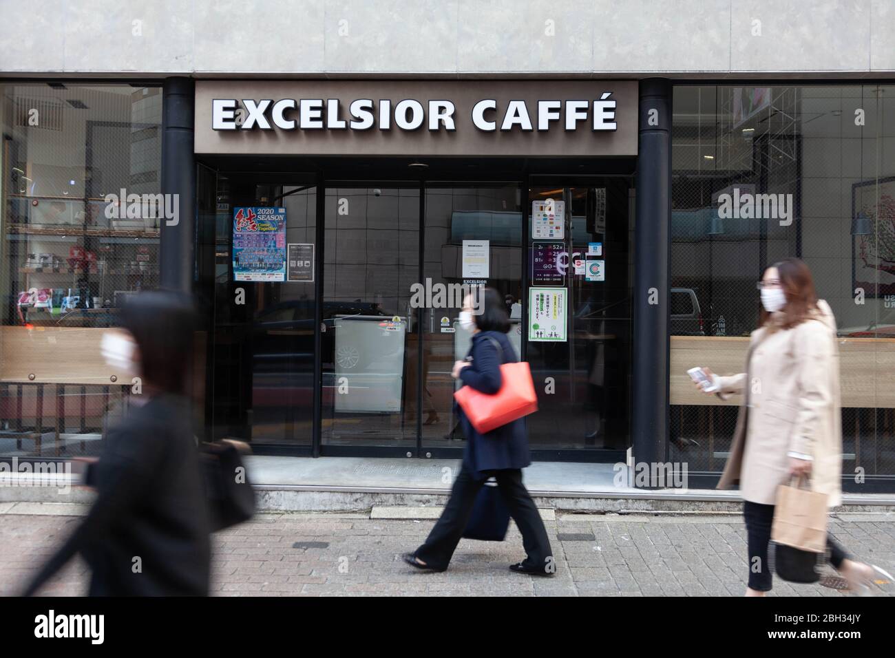 Persone che indossano maschere chirurgiche camminano presso l'Excelsior Cafe a Shibuya, Tokyo, Giappone, che è temporaneamente chiuso a causa della pandemia di coronavirus COVID-19, 8 aprile 2020. Credito fotografo Niclas Ericsson. () Foto Stock