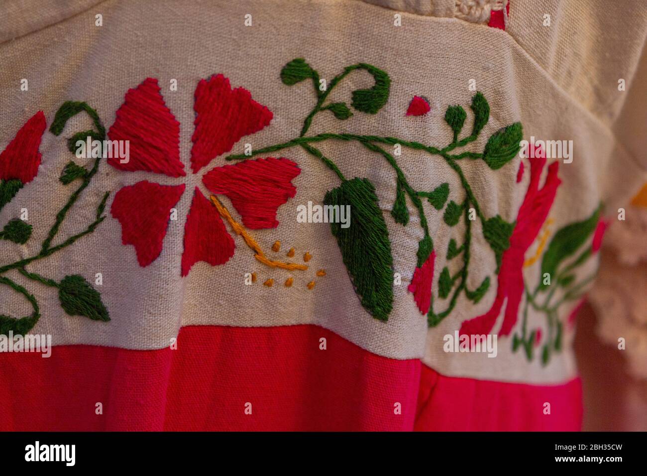 Primo piano su abito Maya decorato con fiori ricamati. Il rosa messicano è tradizionale nell'abbigliamento e nell'arredamento della casa. Foto Stock