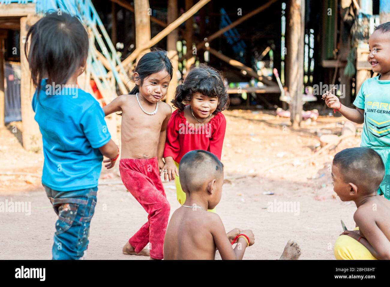 Un piccolo gruppo di bambini cambogiani gioca lungo la strada principale al villaggio galleggiante di Kampong Phluk, vicino al lago Tonle SAP, Cambogia. Foto Stock