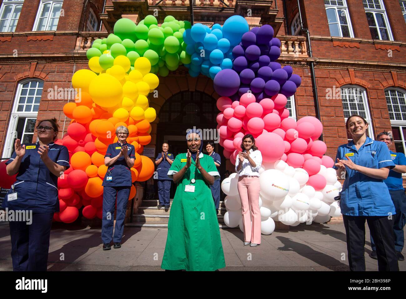 Infermieri, chirurghi, medici e personale di supporto del NHS aiutano a svelare una mostra di palloncini arcobaleno fuori dal National Hospital for Neurology and Neurochirurgical di Holborn, Londra per ringraziare il pubblico per il loro sostegno durante la pandemia di Coronavirus in corso. Foto Stock