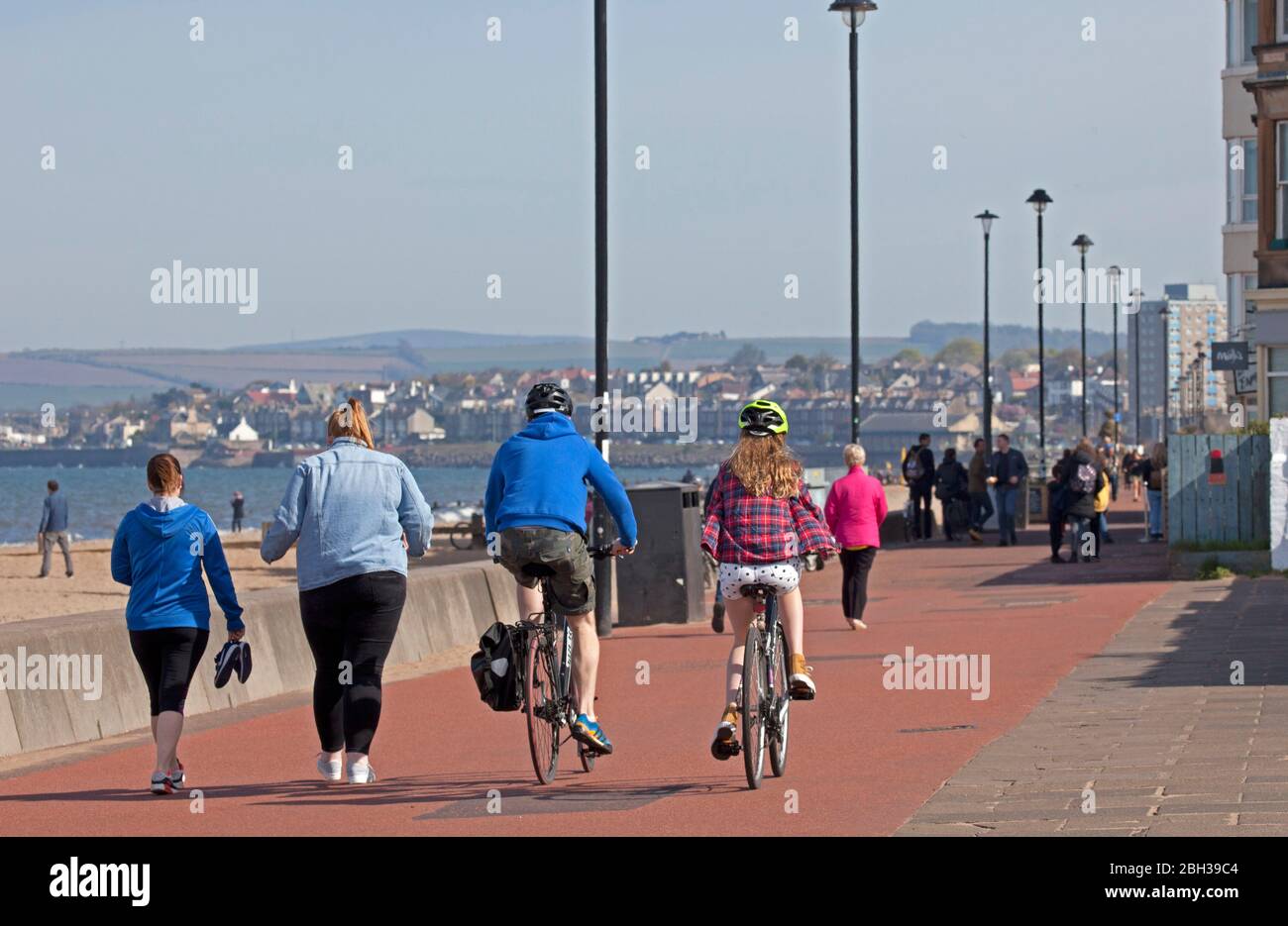 Portobello, Edimburgo, Scozia, Regno Unito. 23 aprile 2020. Pomeriggio soleggiato ma ventilato. Più persone locali si avventurano verso il mare forse incoraggiati dal sole a svolgere il loro esercizio quotidiano permesso, ancora quasi tanti ciclisti come i pedoni sulla Promenade. Foto Stock