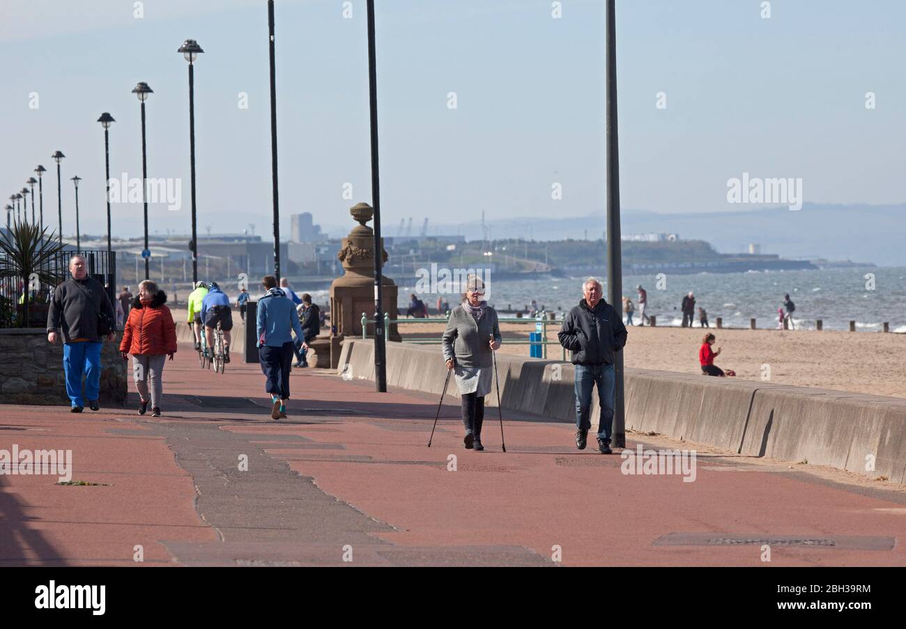 Portobello, Edimburgo, Scozia, Regno Unito. 23 aprile 2020. Pomeriggio soleggiato ma ventilato. Più persone locali si avventurano verso il mare forse incoraggiati dal sole a svolgere il loro esercizio quotidiano permesso, ancora quasi tanti ciclisti come i pedoni sulla Promenade. Foto Stock