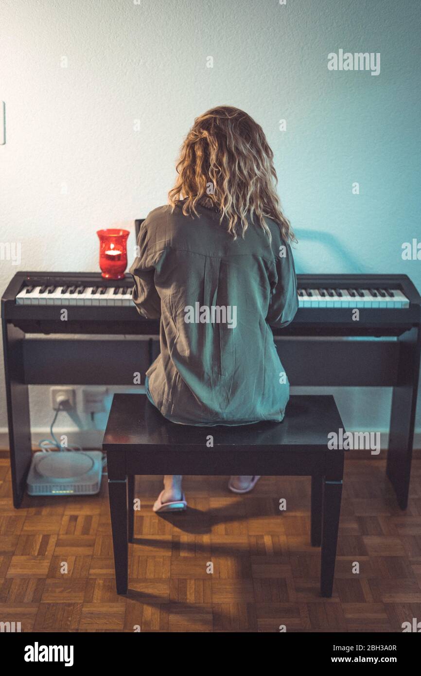 Bella donna suona il pianoforte a casa in giorni limitati Foto Stock