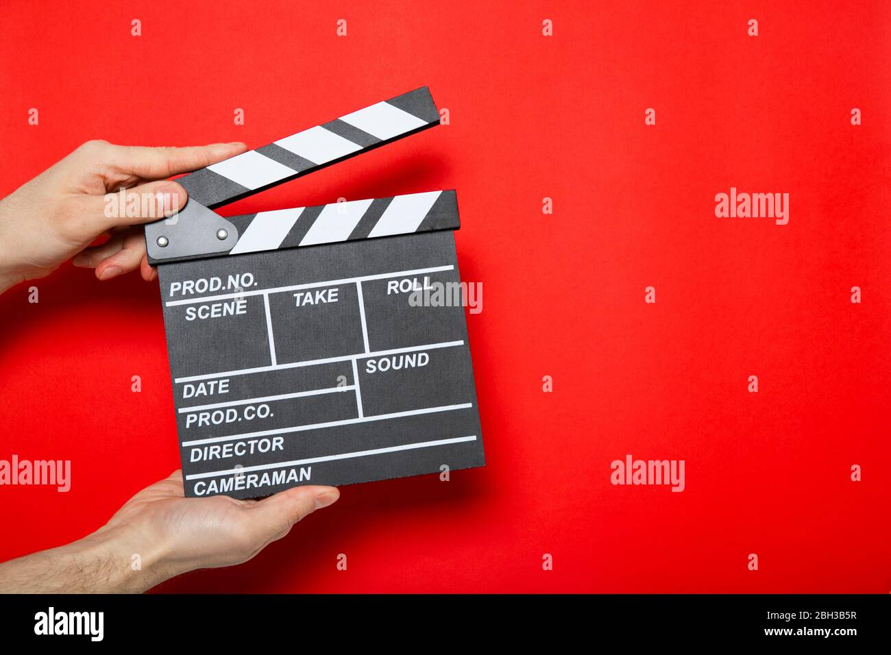 Clapper di film nelle mani di un ragazzo su uno sfondo rosso con posto per il testo Foto Stock