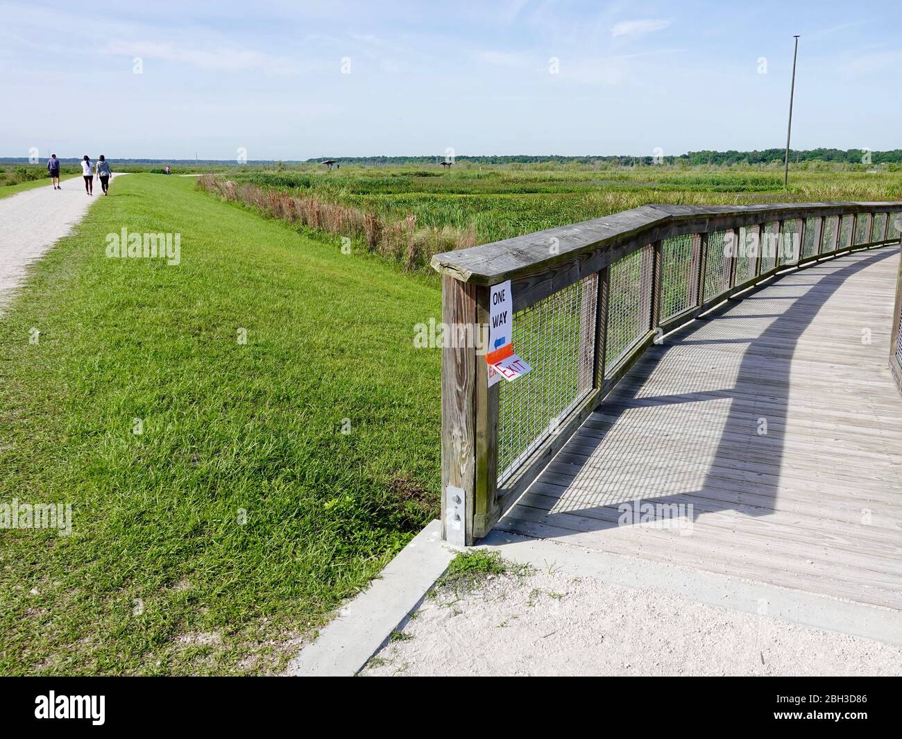 I residenti praticano le distanze sociali sui sentieri di un parco Sweetwater Wetlands, mentre il personale organizza le indicazioni per il traffico pedonale a senso unico. Foto Stock