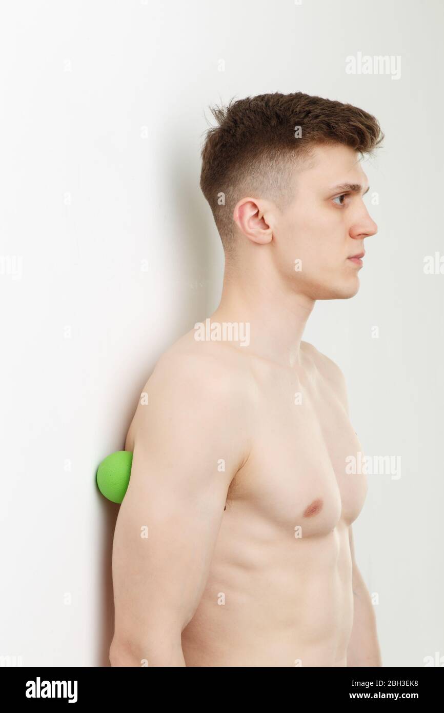 Bell'uomo mostra esercizi utilizzando la parete e la palla per un massaggio miofasciale rilascio dei punti di trigger. Massaggio del muscolo triceps. Foto Stock