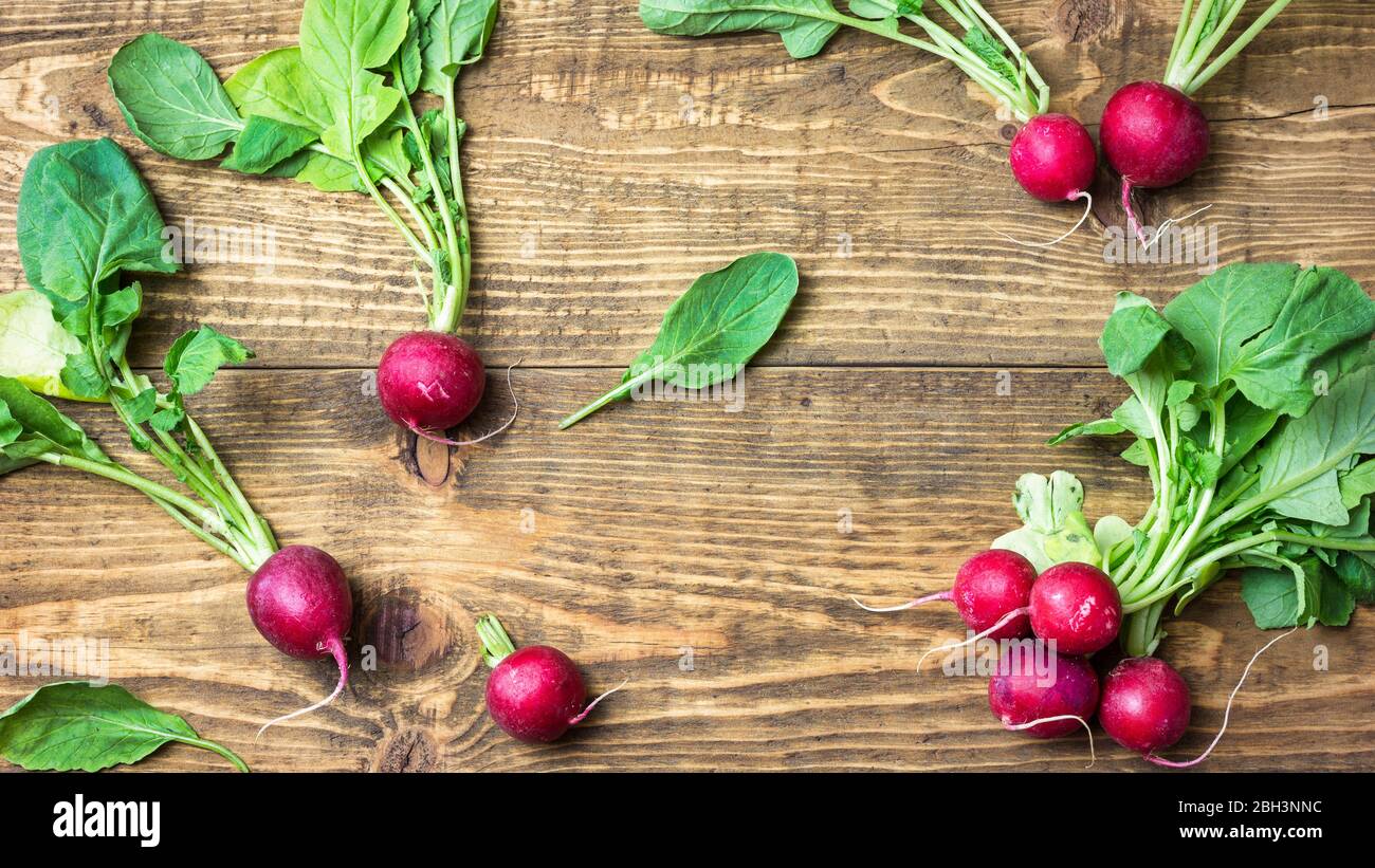 Fresco rosso organico ravanelli con foglie verdi su sfondo rustico in legno. Vista dall'alto con spazio per le copie. Concetto di nutrizione sana. Foto Stock