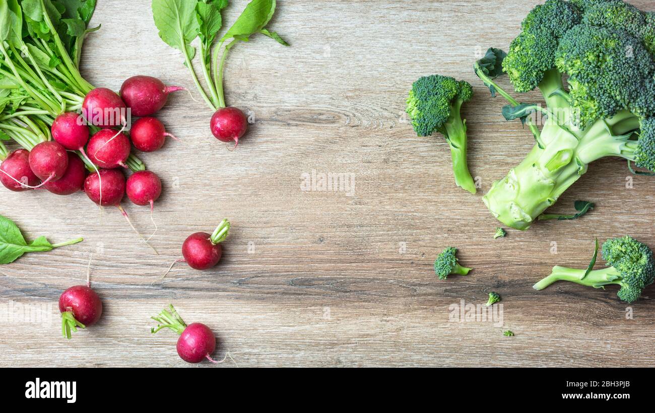 Ravanelli rossi e broccoli biologici freschi su sfondo legno. Vista dall'alto con spazio per le copie. Concetto di nutrizione sana. Foto Stock