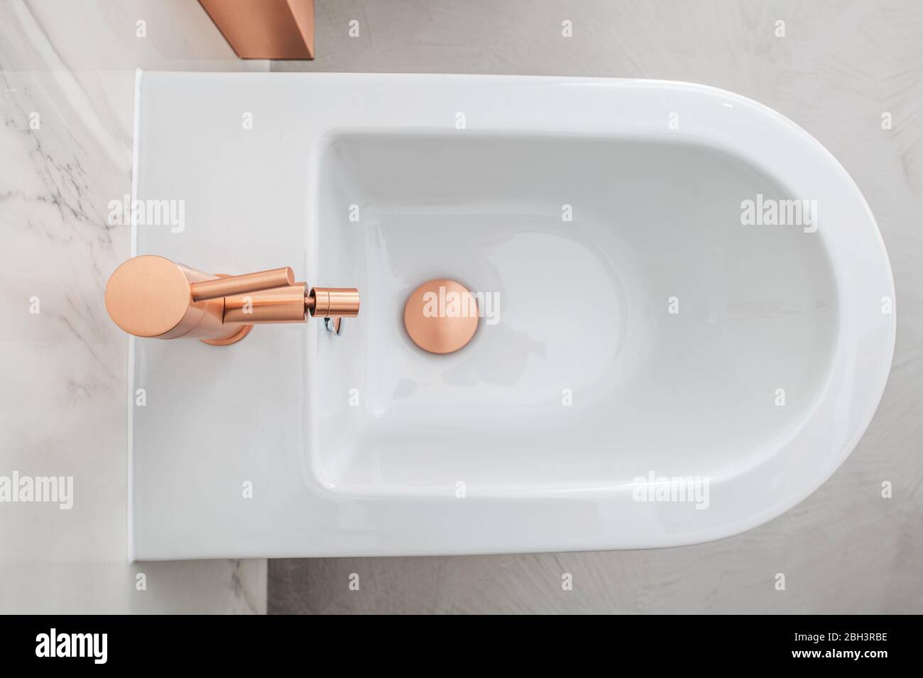 Lussuoso bidet Whote con attrezzatura in rame in bagno piastrella in marmo. Foto Stock