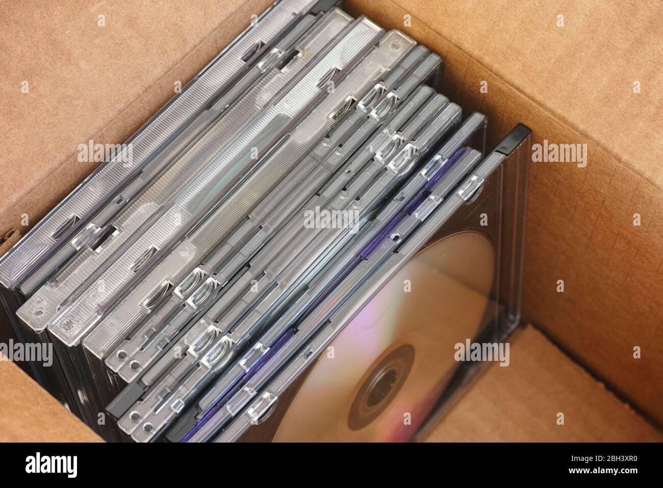 Vecchia collezione di DVD o CD con della polvere su di loro all'interno di una scatola di cartone. Primo piano. Foto Stock