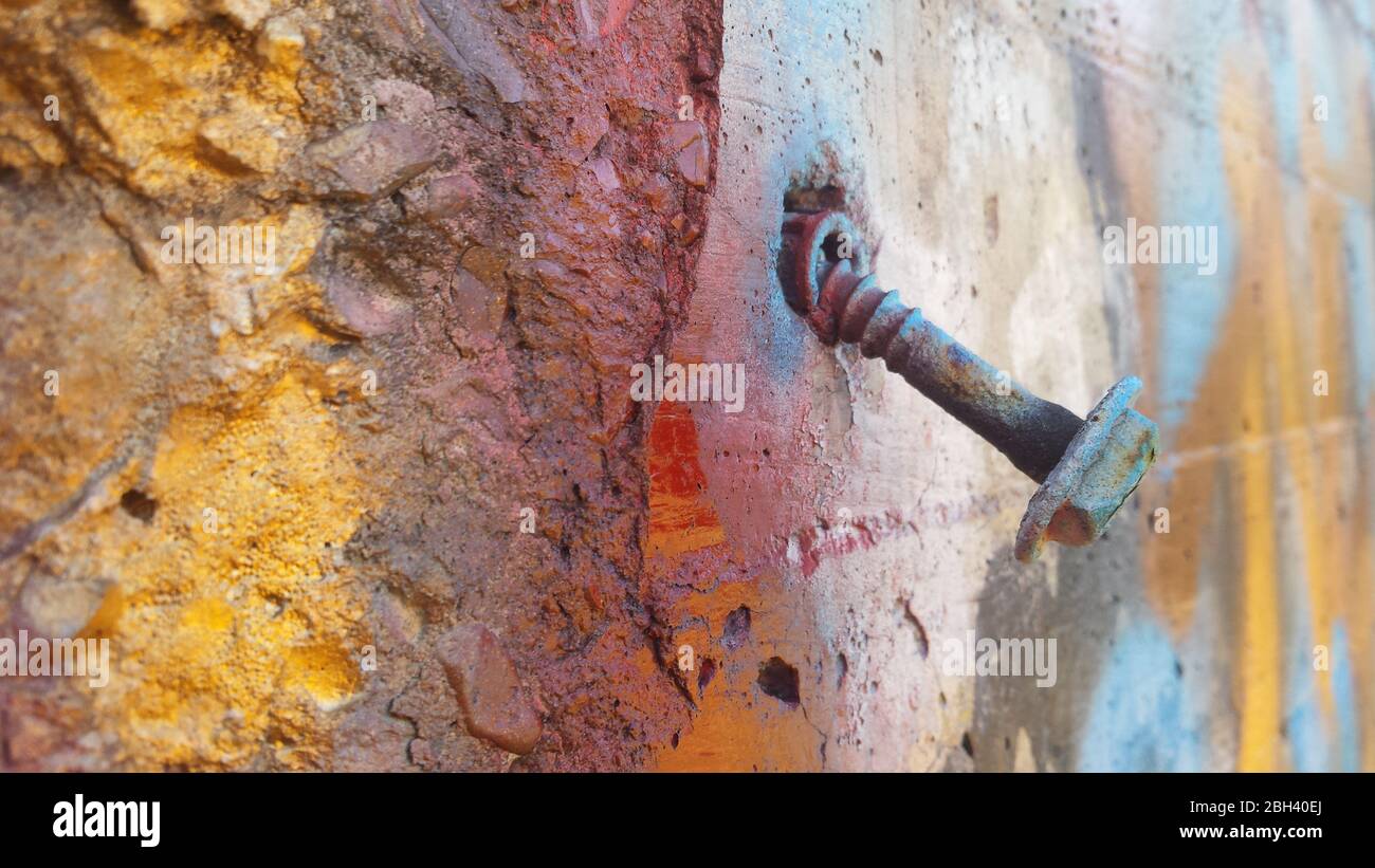 Un edificio condannato in uno stato di decadimento urbano mostra il passare del tempo con questo bullone arrugginito sciolto in una parete esterna Foto Stock