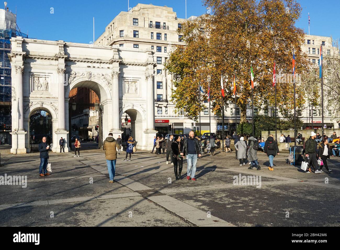 Persone che camminano accanto a Marble Arch, ottocentesco arco trionfale in marmo bianco a Londra Inghilterra Regno Unito Foto Stock