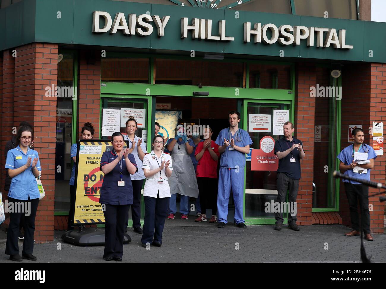 Gli operatori sanitari si scontrano mentre la Bessbrook Crimson Arrow Pipe Band gioca per il personale al di fuori del Daisy Hill Hospital di Newry, Irlanda del Nord, per salutare gli eroi locali durante l'iniziativa Clap for Carers di Giovedi per riconoscere e sostenere gli operatori e gli operatori del NHS che combattono la pandemia del coronavirus. Foto Stock