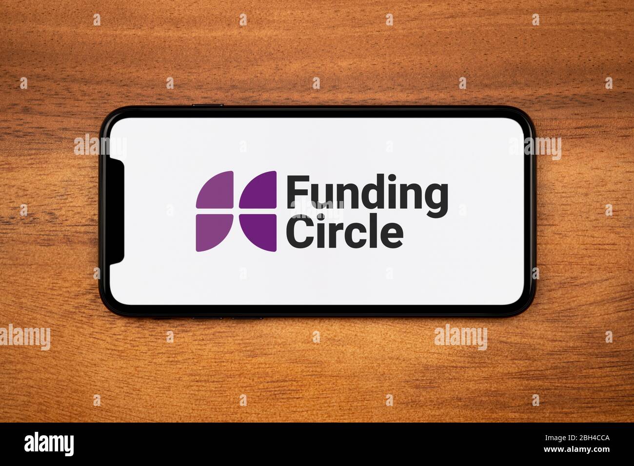Uno smartphone con il logo Funding Circle poggia su un tavolo di legno (solo per uso editoriale). Foto Stock