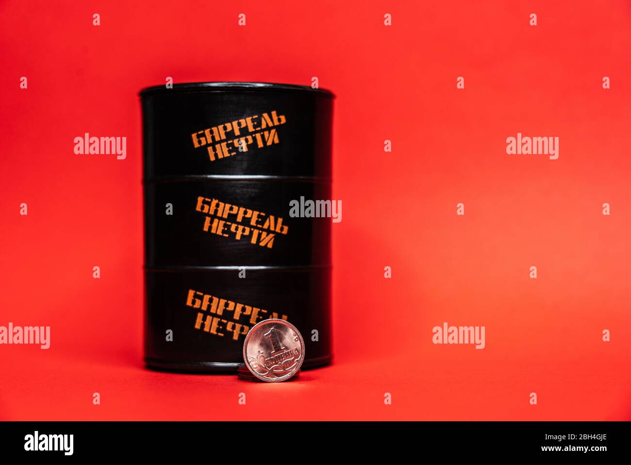 Barile nero con una moneta da un solo centesimo su sfondo rosso. Il prezzo al barile del petrolio scende sotto grafico. Andamento del mercato petrolifero. Infografica sul petrolio. Foto Stock