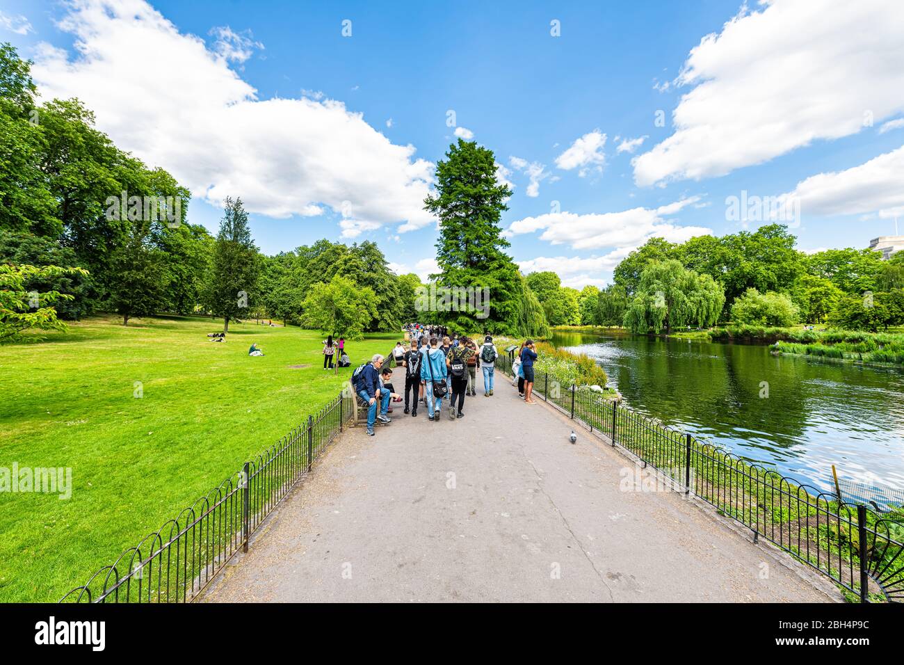 Londra, UK - 21 giugno 2018: Saint James Park verde erba e alberi in estate soleggiata con molte persone a piedi sul marciapiede da stagno fiume acqua Foto Stock