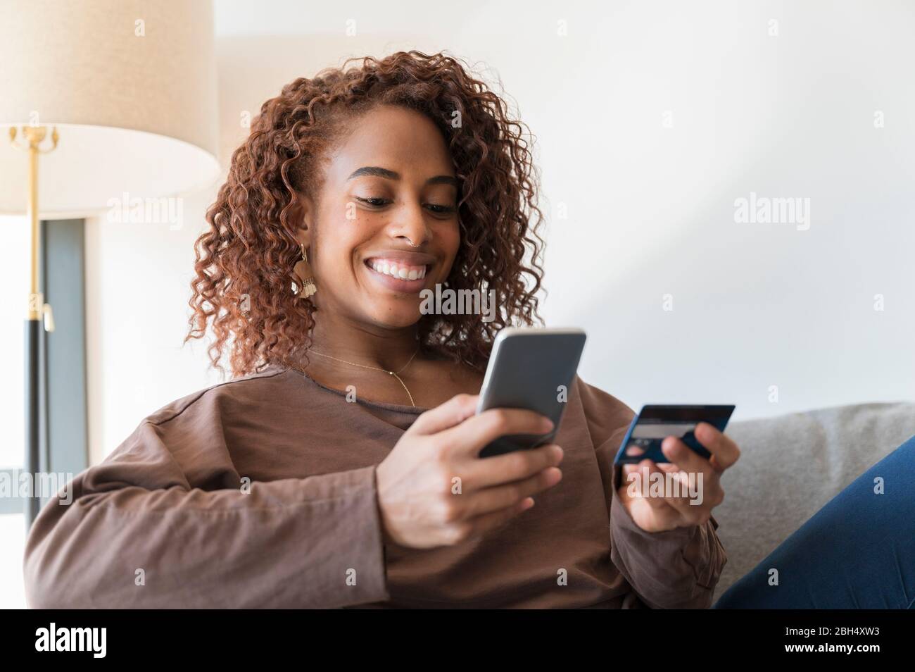 Donna sorridente con carta di credito e smartphone Foto Stock
