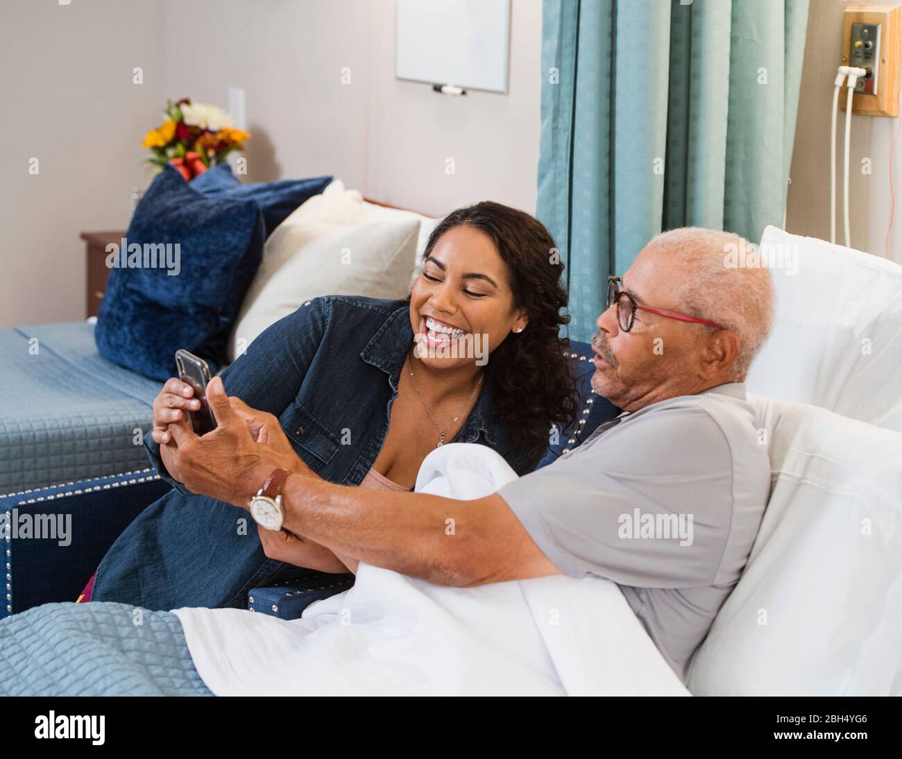 Donna sorridente e uomo anziano sorridente che guarda lo smartphone Foto Stock
