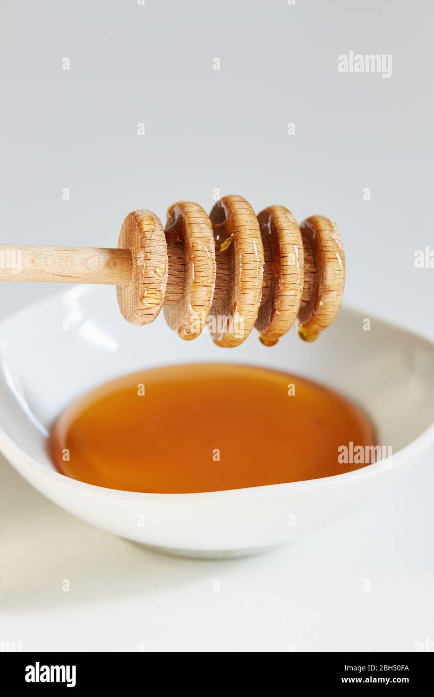 Cucchiaia di miele su ciotola di miele Foto Stock