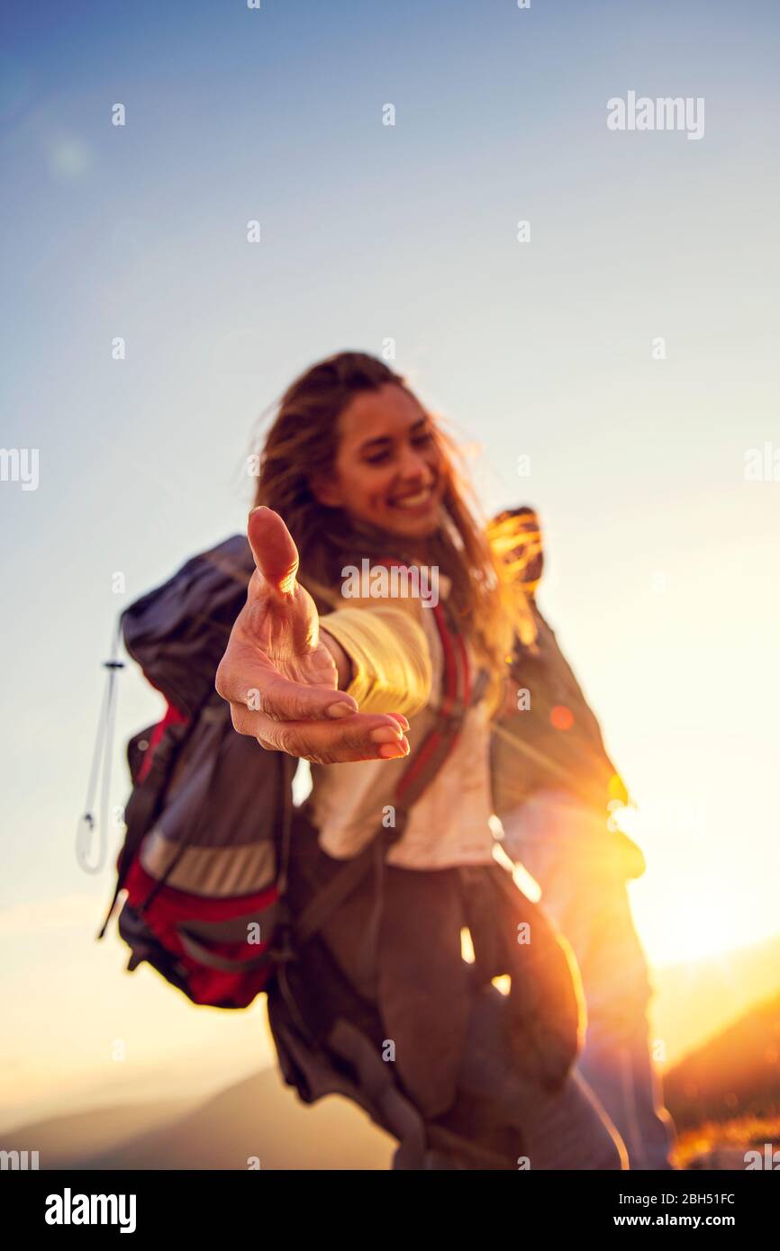 Persone che si aiutano a camminare su una montagna all'alba. Foto Stock