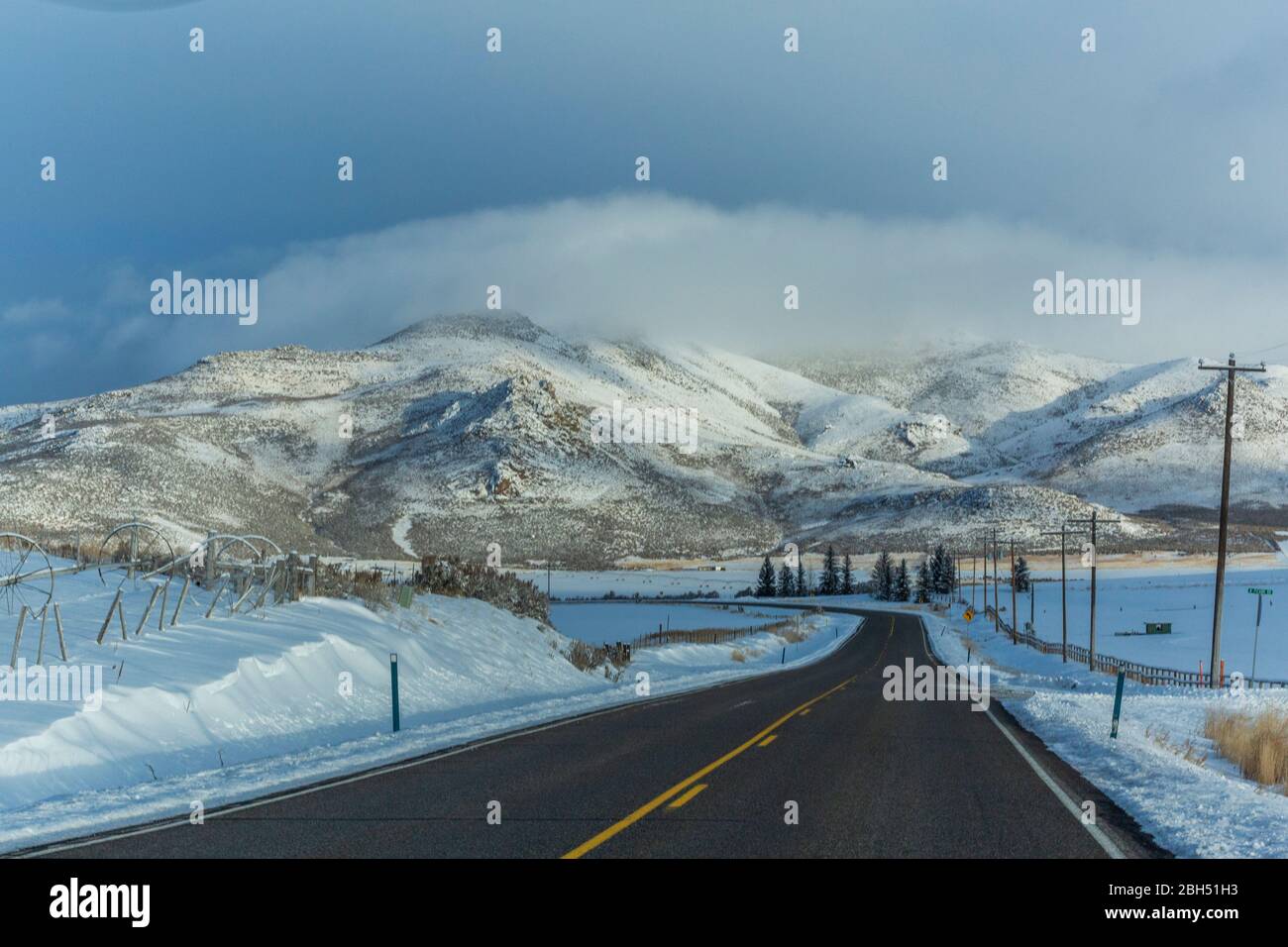 Strada con montagne innevate in lontananza Foto Stock