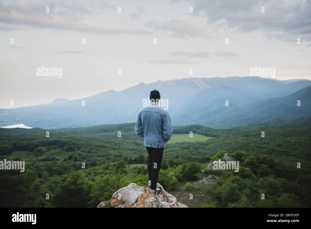 Uomo in piedi su una scogliera in montagna e nella foresta Foto Stock