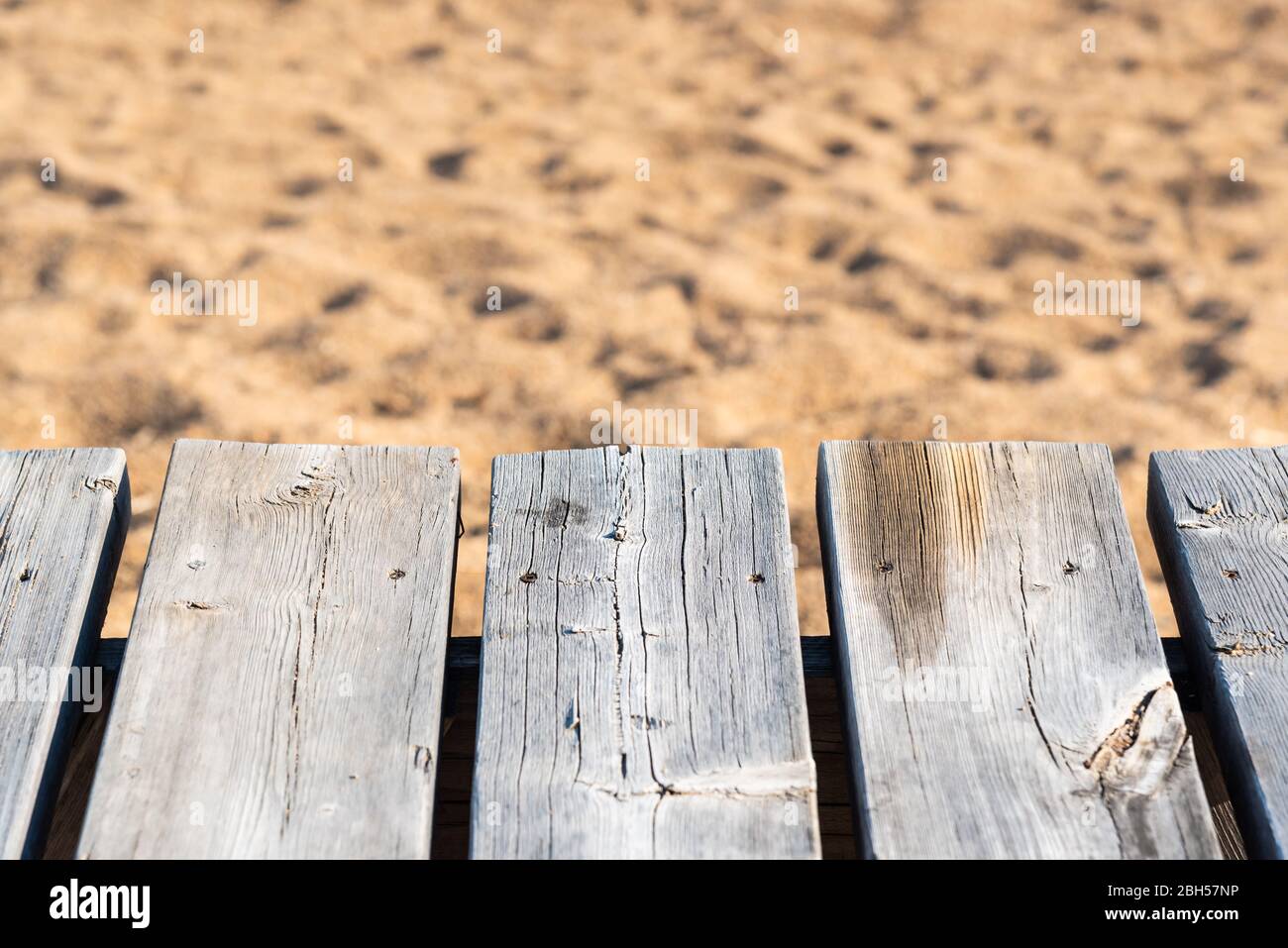 Primo piano di legno grigio e stagionato con sabbia sulla spiaggia sullo sfondo Foto Stock