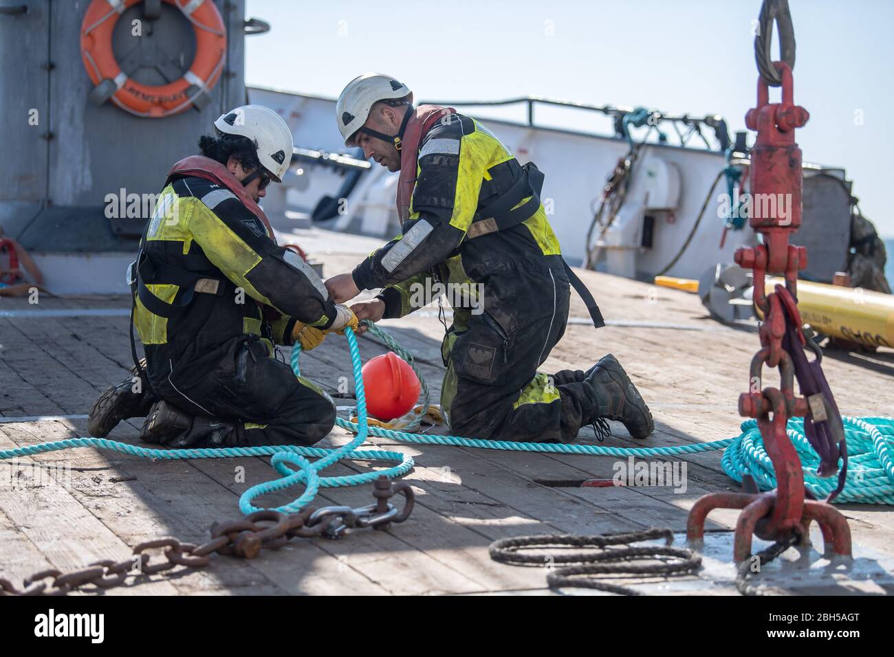 23 aprile 2020, Schleswig-Holstein, Helgoland: Due operai preparano la corda per una tonnellata. Segnale di partenza per un grande campo di test marittimo al largo di Helgoland: Gli scienziati del Centro di test per le tecnologie marittime hanno utilizzato tonnellate per contrassegnare un'area di tre milioni di metri quadrati non lontano dall'isola del Mare del Nord. Esso è destinato a fornire in futuro impianti di prova per la robotica marittima. Produttori e scienziati possono testare diversi scenari. Ad esempio, i veicoli subacquei autonomi per turbine eoliche offshore possono essere testati in condizioni reali in mare o droni che volano sul w Foto Stock