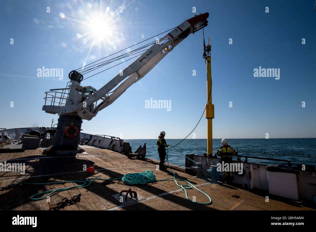 23 aprile 2020, Schleswig-Holstein, Helgoland: Una tonnellata è abbassata nell'acqua con l'aiuto di una gru. Segnale di partenza per un grande campo di test marittimo al largo di Helgoland: Gli scienziati del Centro di test per le tecnologie marittime hanno utilizzato tonnellate per contrassegnare un'area di tre milioni di metri quadrati non lontano dall'isola del Mare del Nord. Esso è destinato a fornire in futuro impianti di prova per la robotica marittima. Produttori e scienziati possono testare diversi scenari. Ad esempio, i veicoli subacquei autonomi per turbine eoliche offshore possono essere testati in condizioni reali in mare o droni flyi Foto Stock