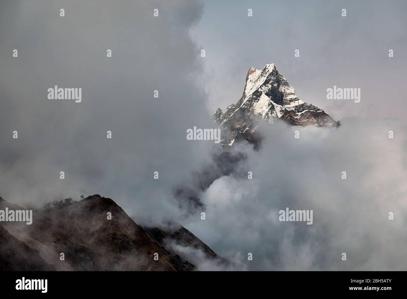 Pesce Machapuchare picco racconto circondato da nuvole in Himalaya, Nepal. Foto Stock