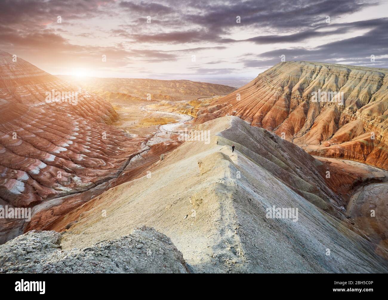 Turismo a piedi il sentiero di giallo surreale montagne al tramonto nel parco deserto Altyn Emel in Kazakistan Foto Stock