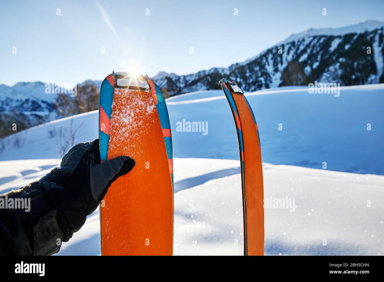 Coppia di sci nella neve con orange camus alla mattina di sole in montagna Foto Stock