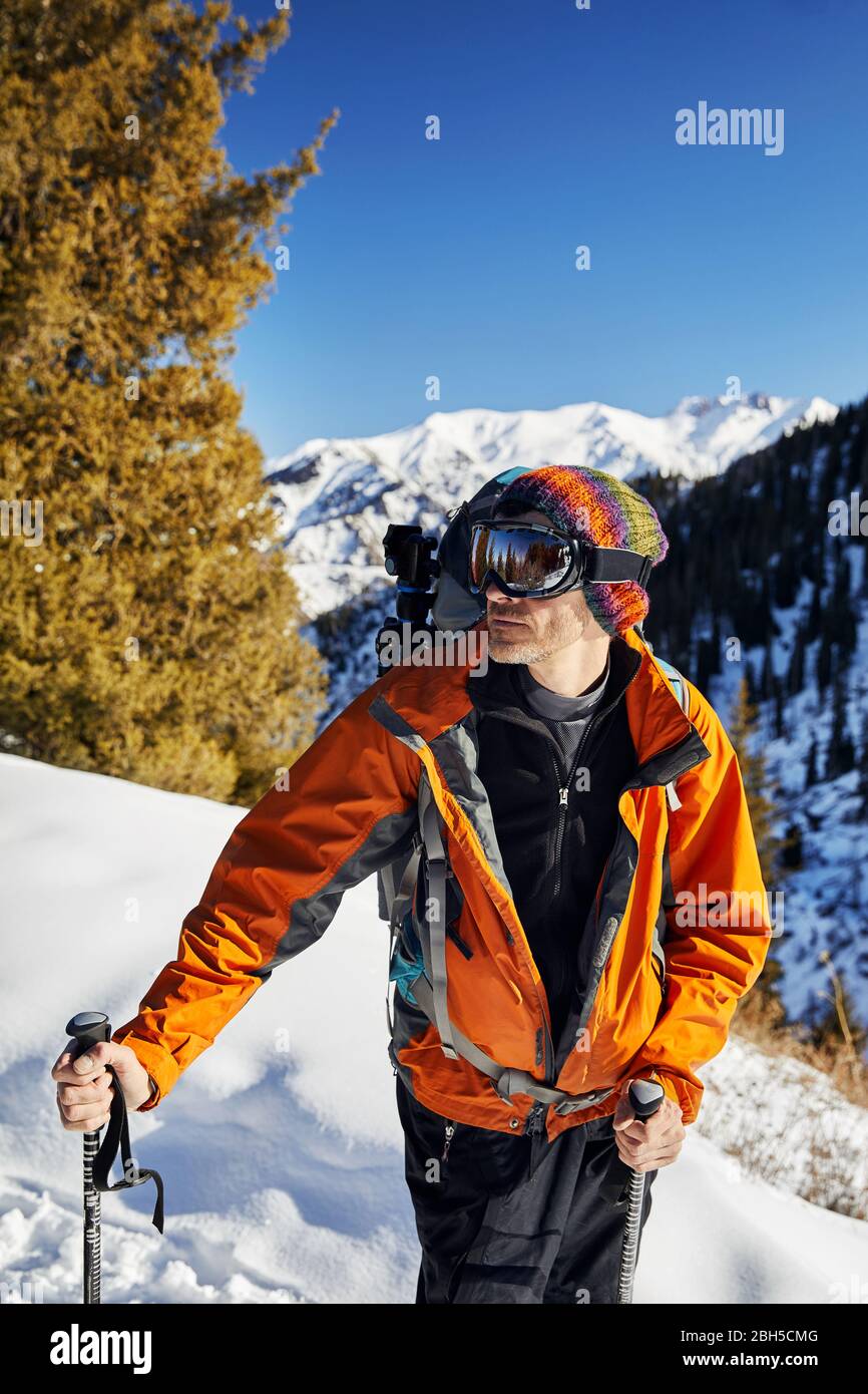 Ritratto di sciatore in camicia arancione e la maschera alla montagna di neve sullo sfondo a giornata di sole Foto Stock