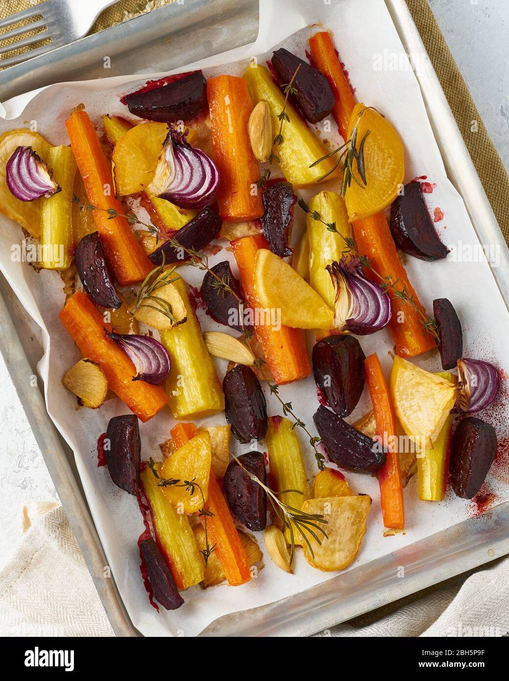 Verdure arrostite colorate su vassoio con pergamena. Mix di carote, barbabietole, rape Foto Stock