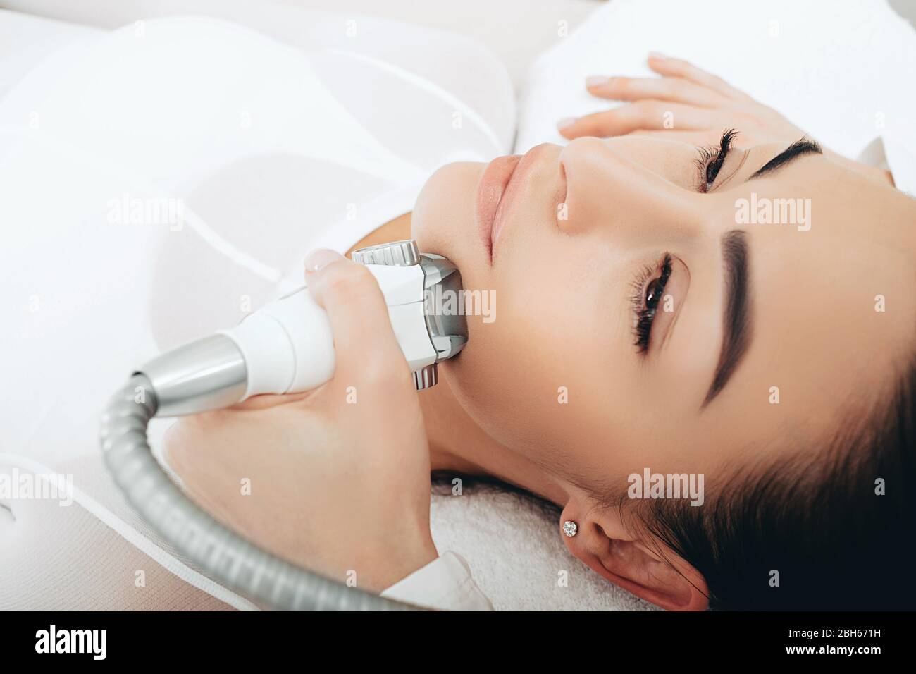 Utilizzando l'apparecchio GPL, il beautician effettua un massaggio di sollevamento del viso. Sollevamento del contorno del viso, primo piano Foto Stock