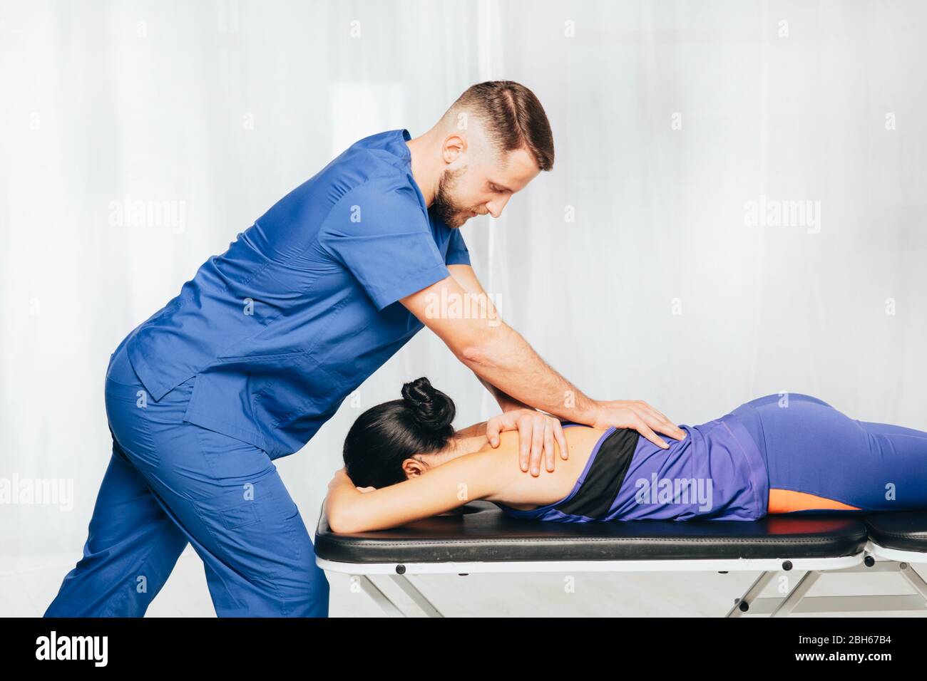 Fisioterapista dando massaggio alla schiena al paziente di sesso femminile Foto Stock