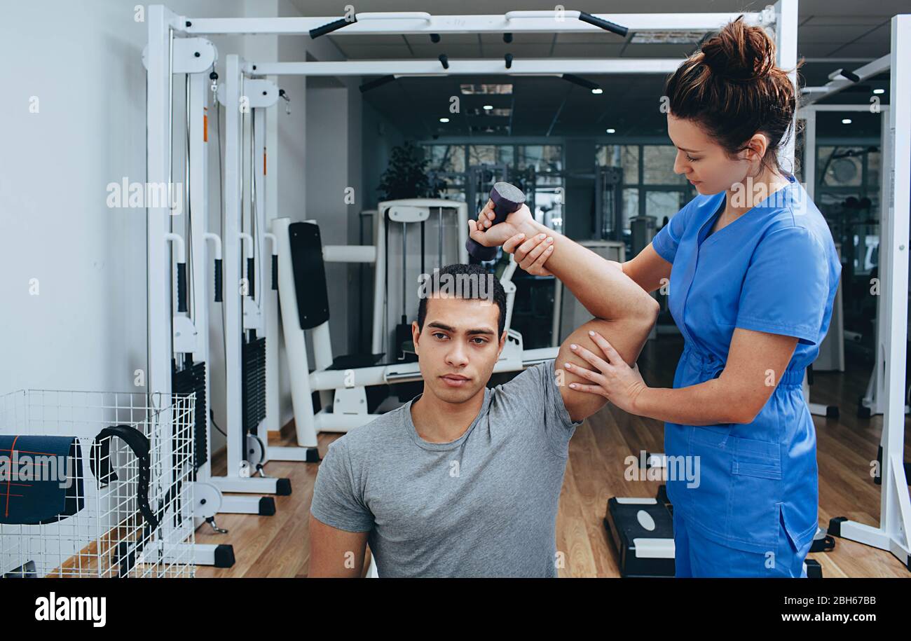 Atleta di gare miste con una lesione alla spalla in un centro di riabilitazione. Fisioterapista aiuta a recuperare dopo una lesione Foto Stock