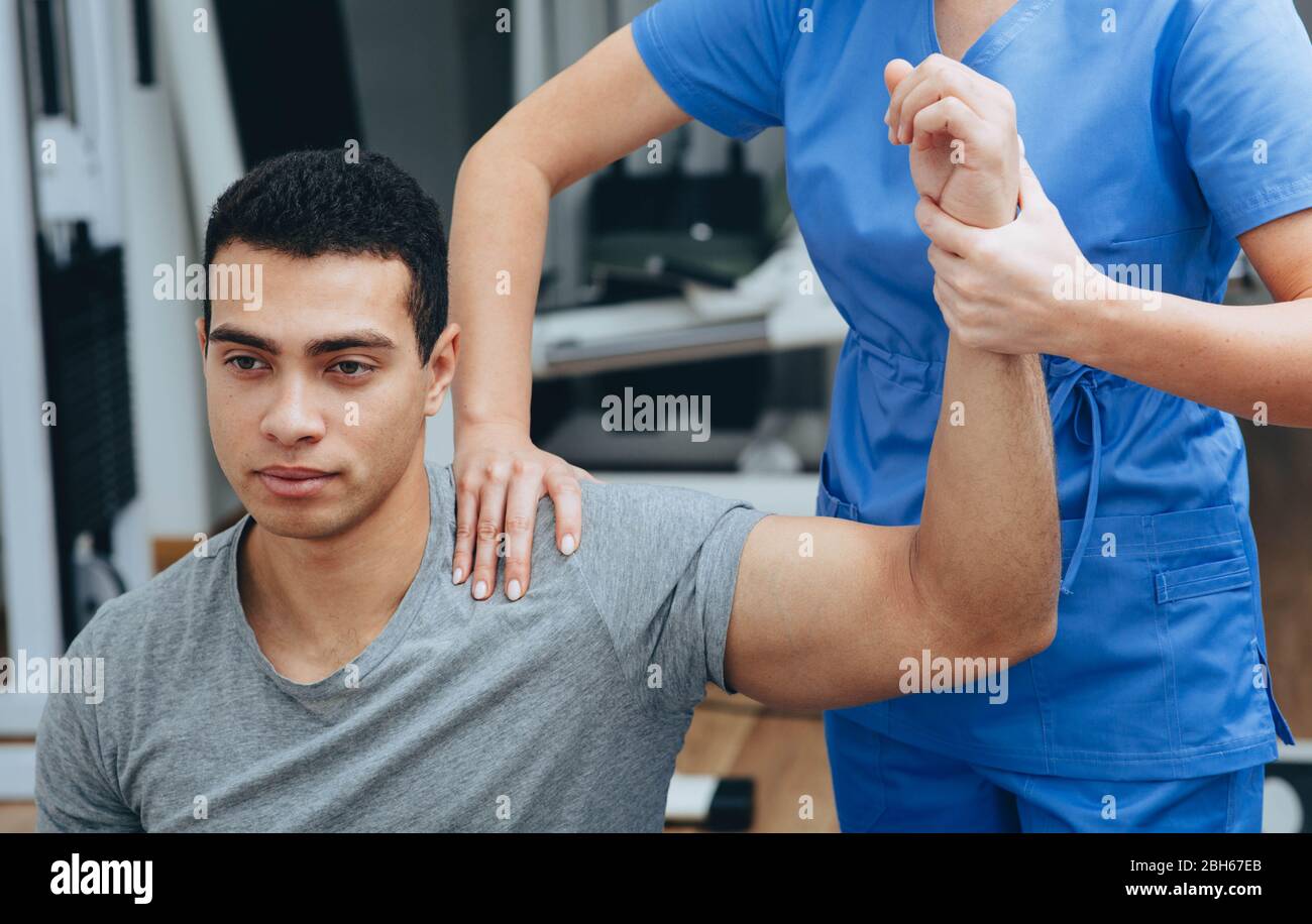 Atleta di gare miste con lesioni alle spalle in un centro di riabilitazione. Fisioterapista aiuta a recuperare dopo una lesione Foto Stock