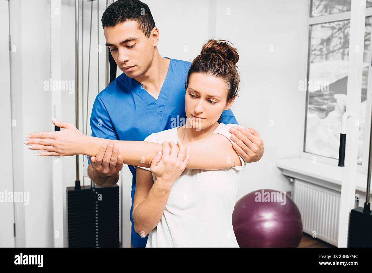 Donna con lesioni al giunto a gomito. Dolore articolare. Fisioterapista tiene la mano di una donna durante la riabilitazione Foto Stock