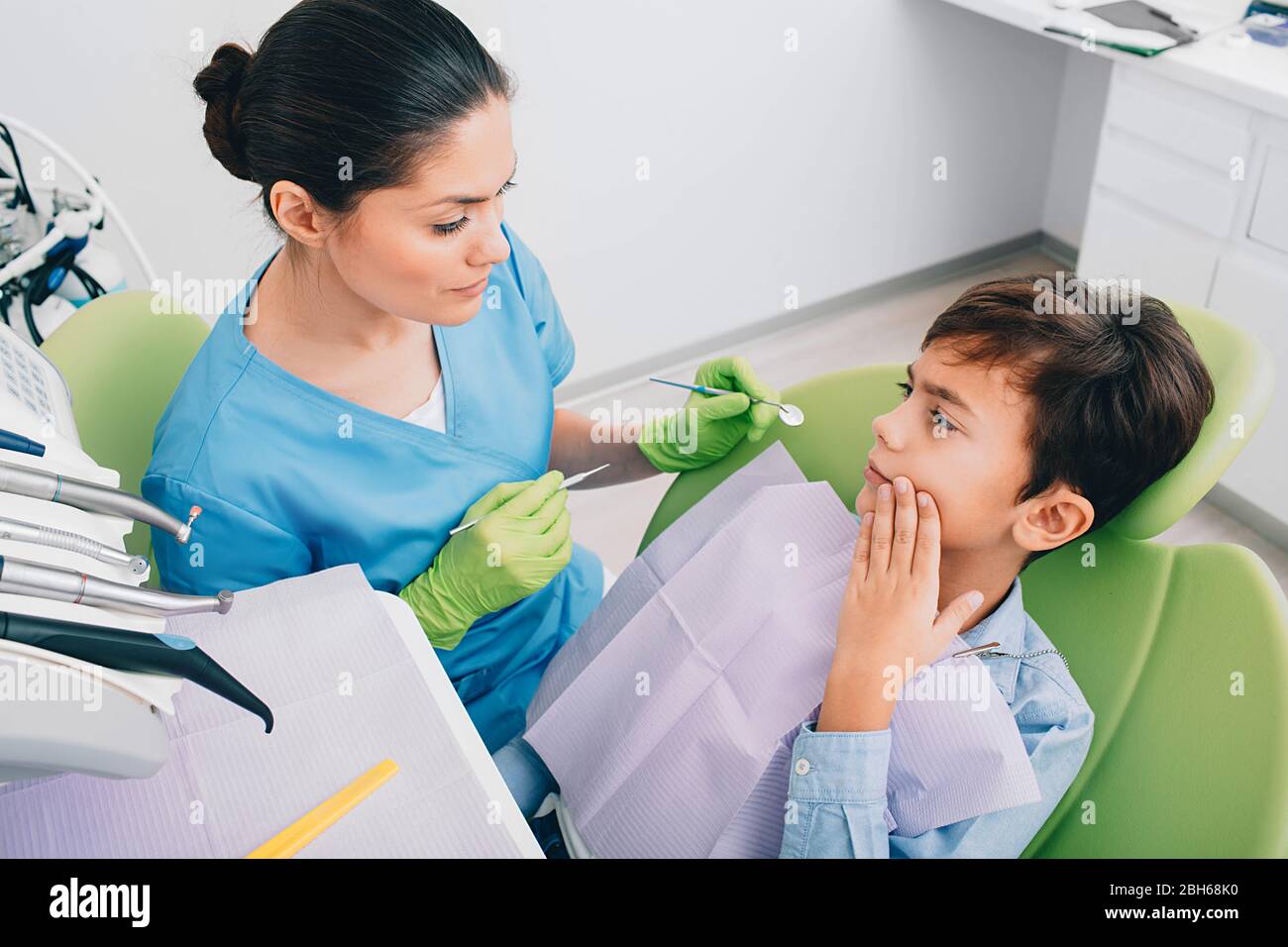 Tristezza ragazzino che mostra dolore ai denti al dentista. Ha visitato il dentista del pediatra Foto Stock