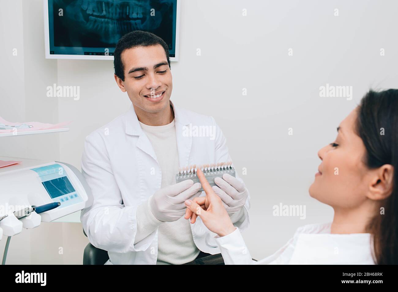 Dentista campionamento sfumature denti, tiene denti tavolozza sfumature vicino bocca femmina Foto Stock