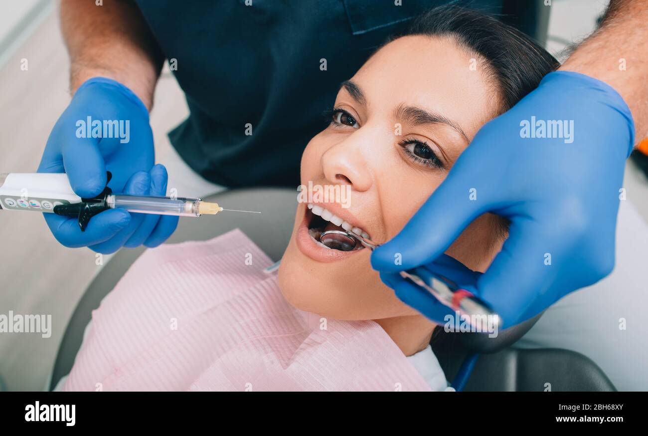 Donna che ottiene anestesia dei denti di procedura dal suo dentista. Trattamento dei denti senza dolore Foto Stock